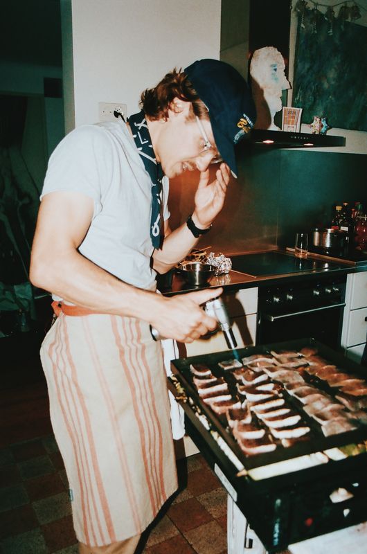 Un cuisinier en tablier rayé saisit la viande au chalumeau dans la cuisine
