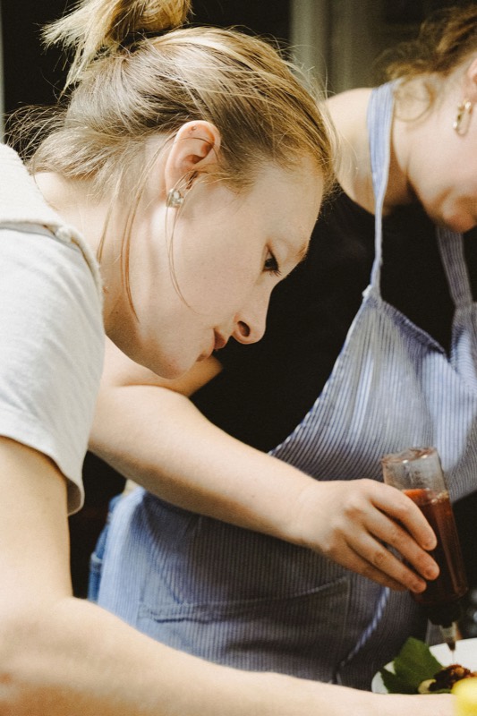 Une cuisinière en tablier se penche sur les assiettes