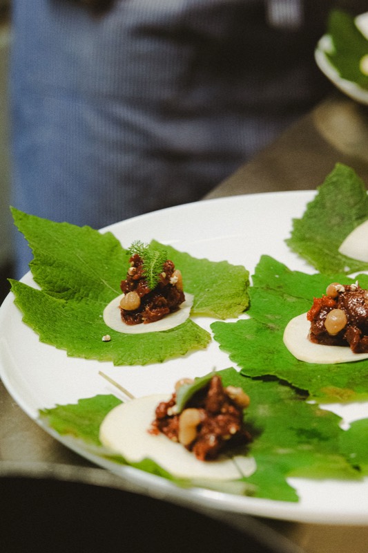 Bouchées de tartare de chevreuil sur des feuilles vertes, sur un grand plat blanc
