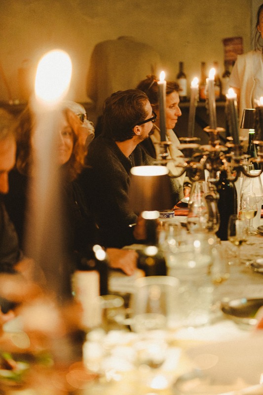 Des convives à la lueur des bougies, verres et bouteilles sur la table