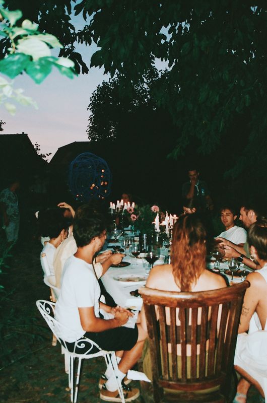 La grande table au crépuscule, bougies allumées, les convives de dos